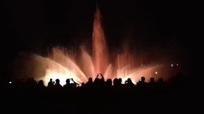 Nighttime view of Qidra’s illuminated fountain show, with crowds gathered around enjoying the spectacle.