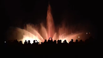 Nighttime view of Qidra’s illuminated fountain show, with crowds gathered around enjoying the spectacle.