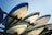 A stack of several speedboats are stored on metal racks under a clear blue sky. The boats are positioned upside down, showing their hulls which have different colors and markings.