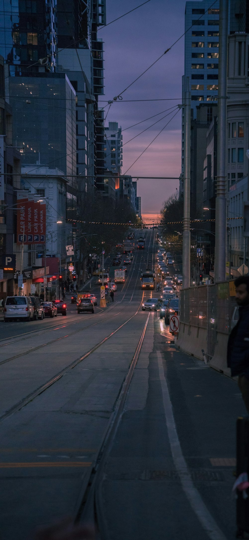 a city street at dusk with a train on the tracks