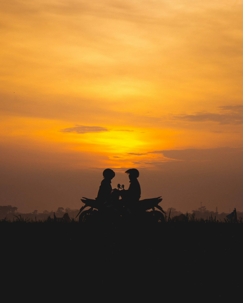 silhouette of man and woman riding motorcycle during sunset
