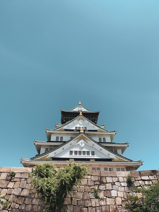 white and green concrete building under blue sky during daytime in Osaka Castle Park Japan