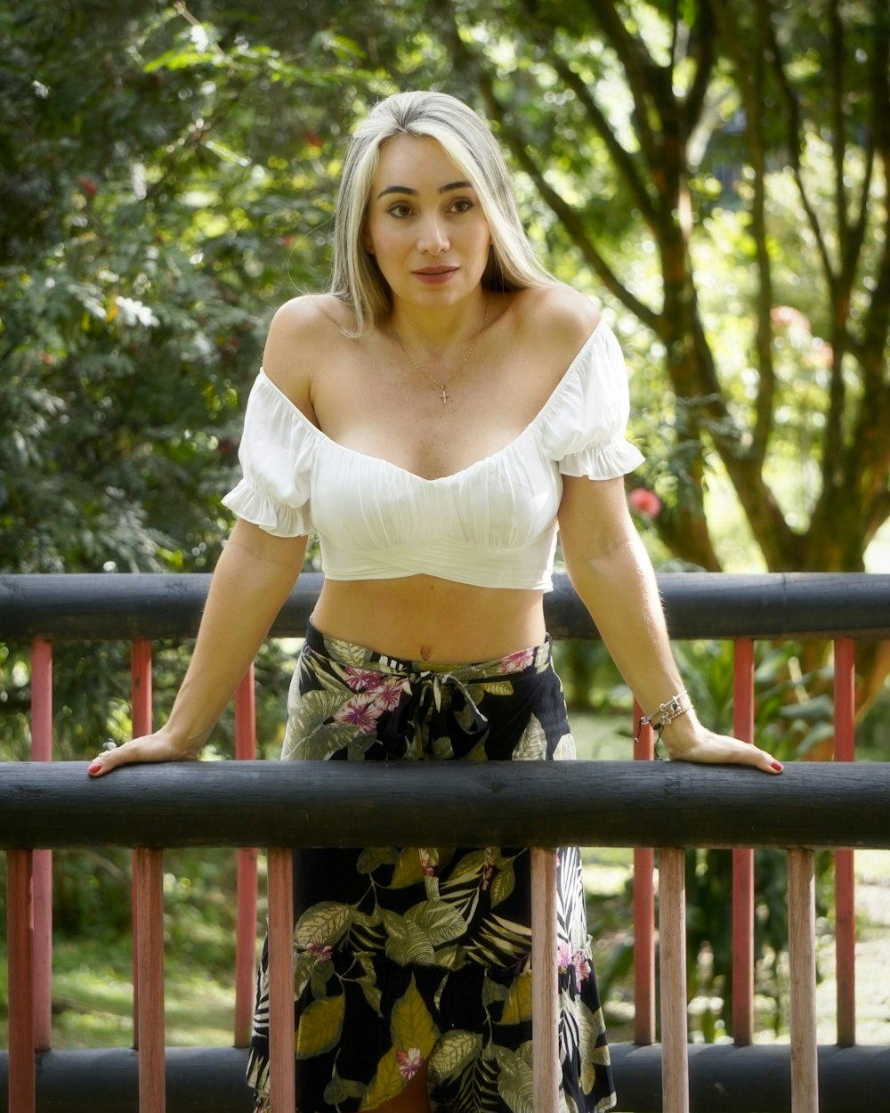 Femme en crop top blanc et jupe fleurie noire debout sur un pont en bois marron pendant la journée