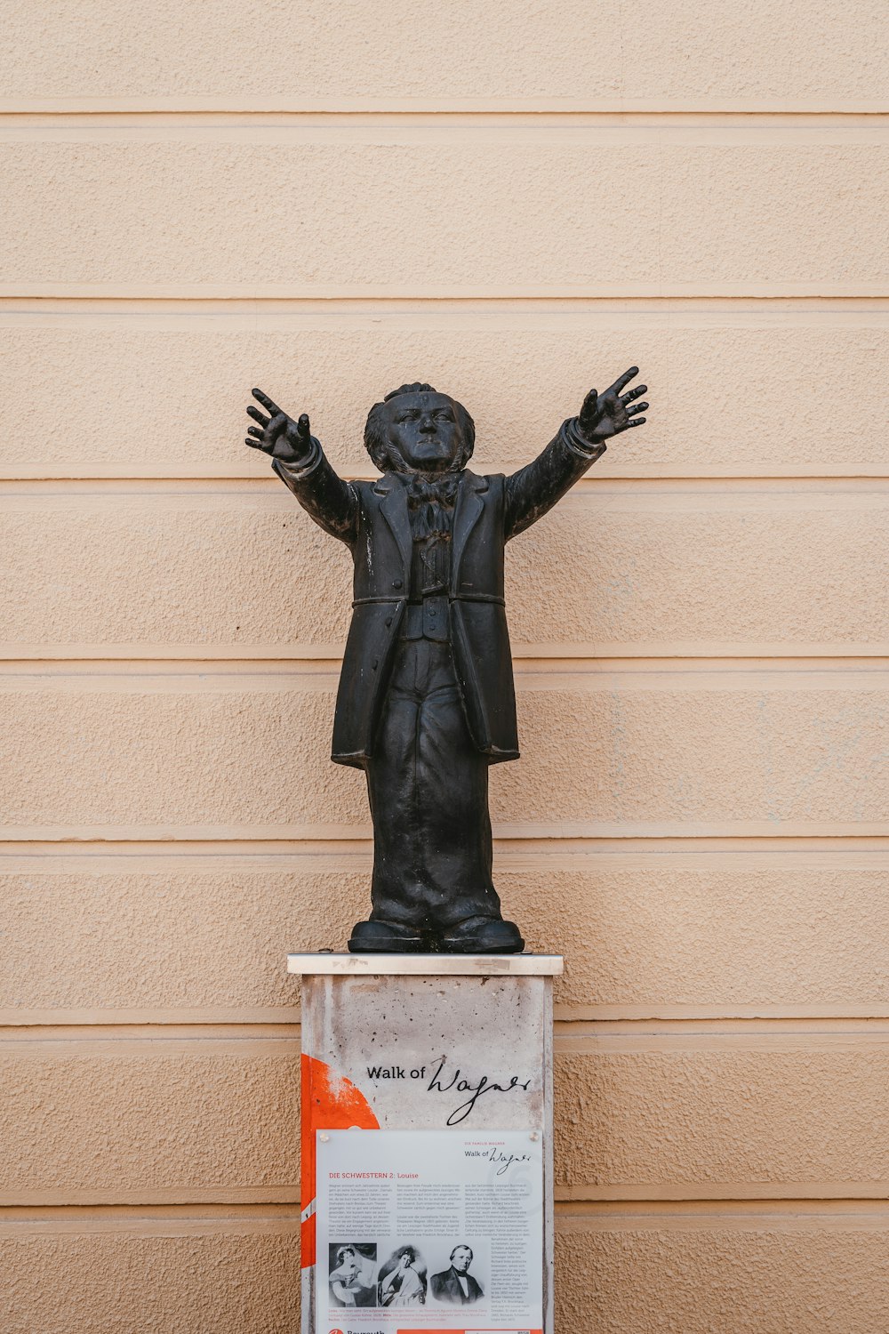 Estatua negra del hombre en la pared de hormigón blanco