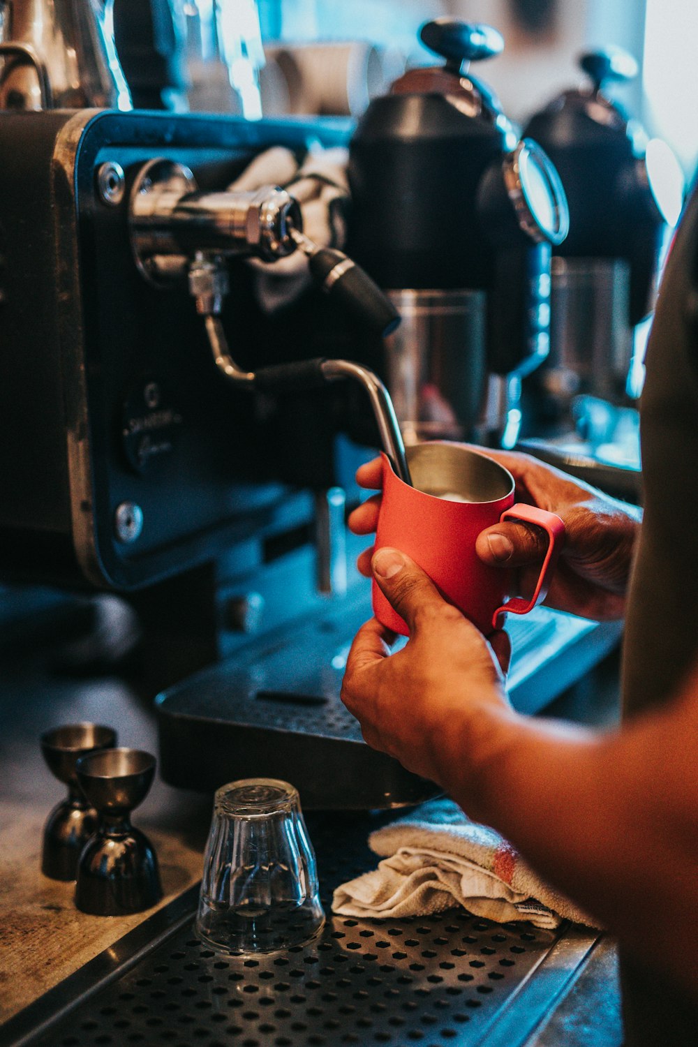 person pouring water on red ceramic mug