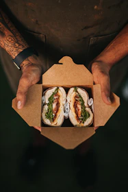 Delivery person handing over a handwiches box to a happy customer.