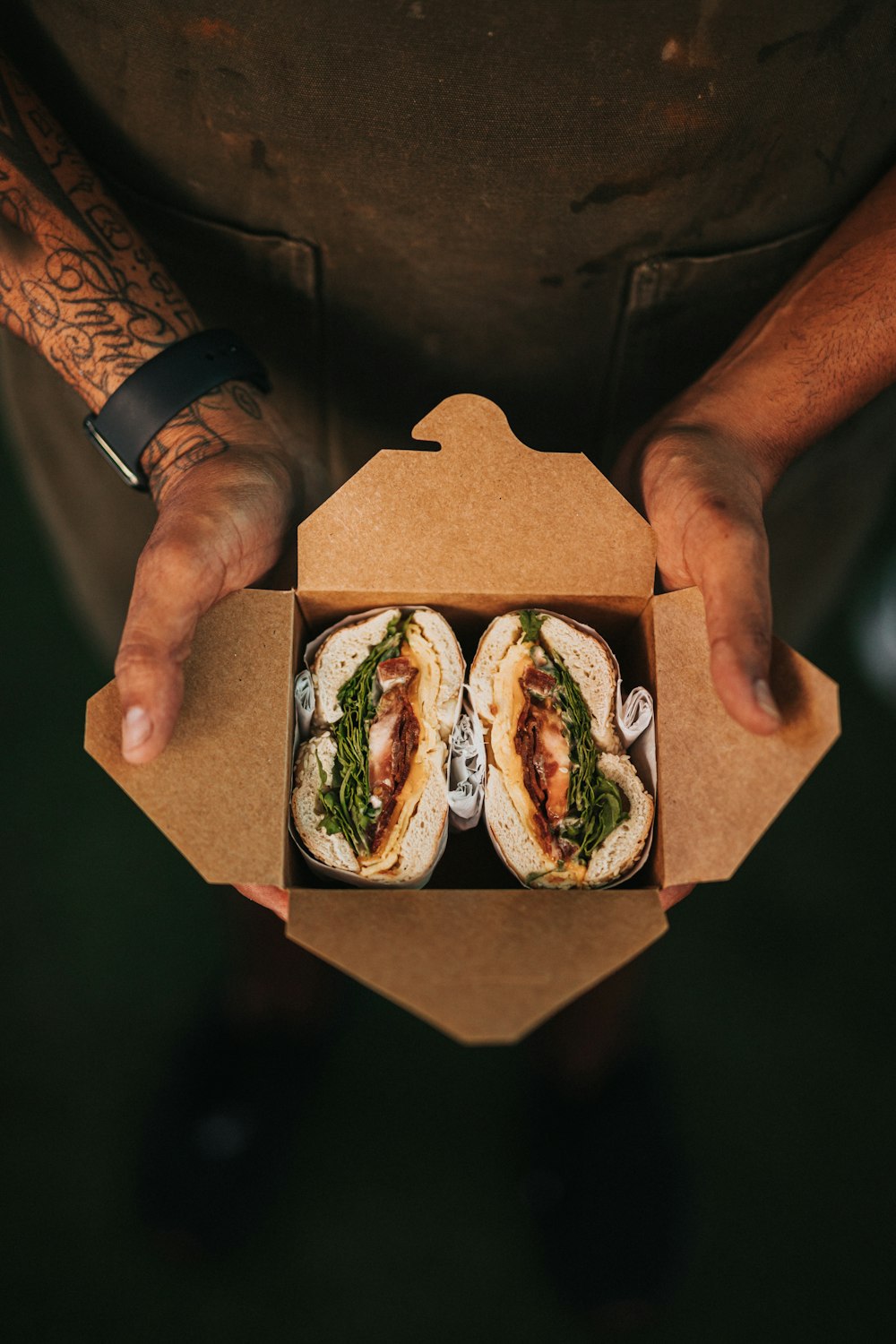 person holding brown cardboard box with burger