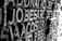 A close-up view of a textured surface featuring intricately carved letters. The lighting casts shadows that enhance the three-dimensional effect of the carving, creating contrast between light and dark areas.