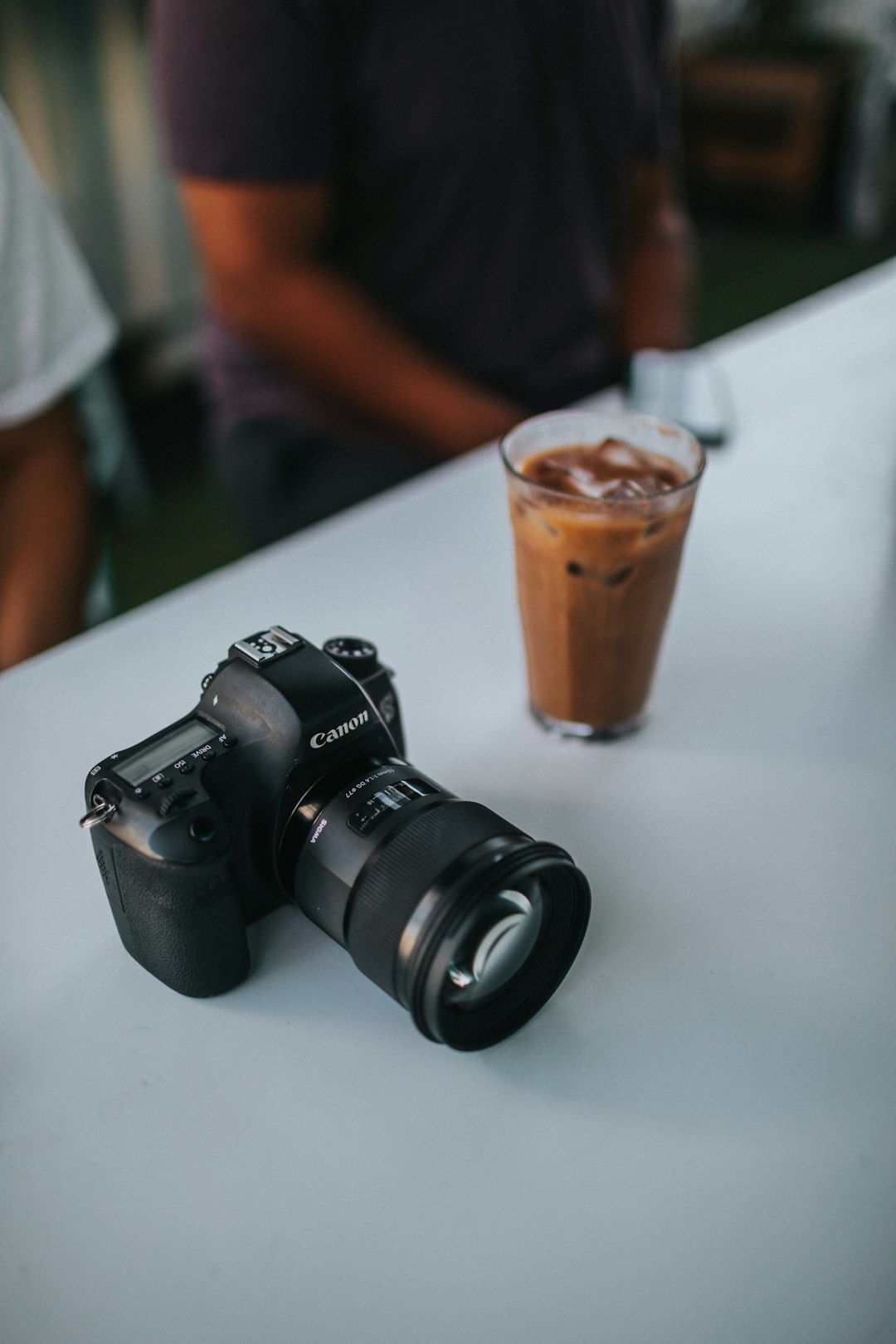 black nikon dslr camera beside brown disposable cup on white table