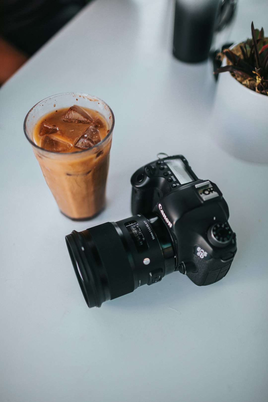black nikon dslr camera beside brown disposable cup