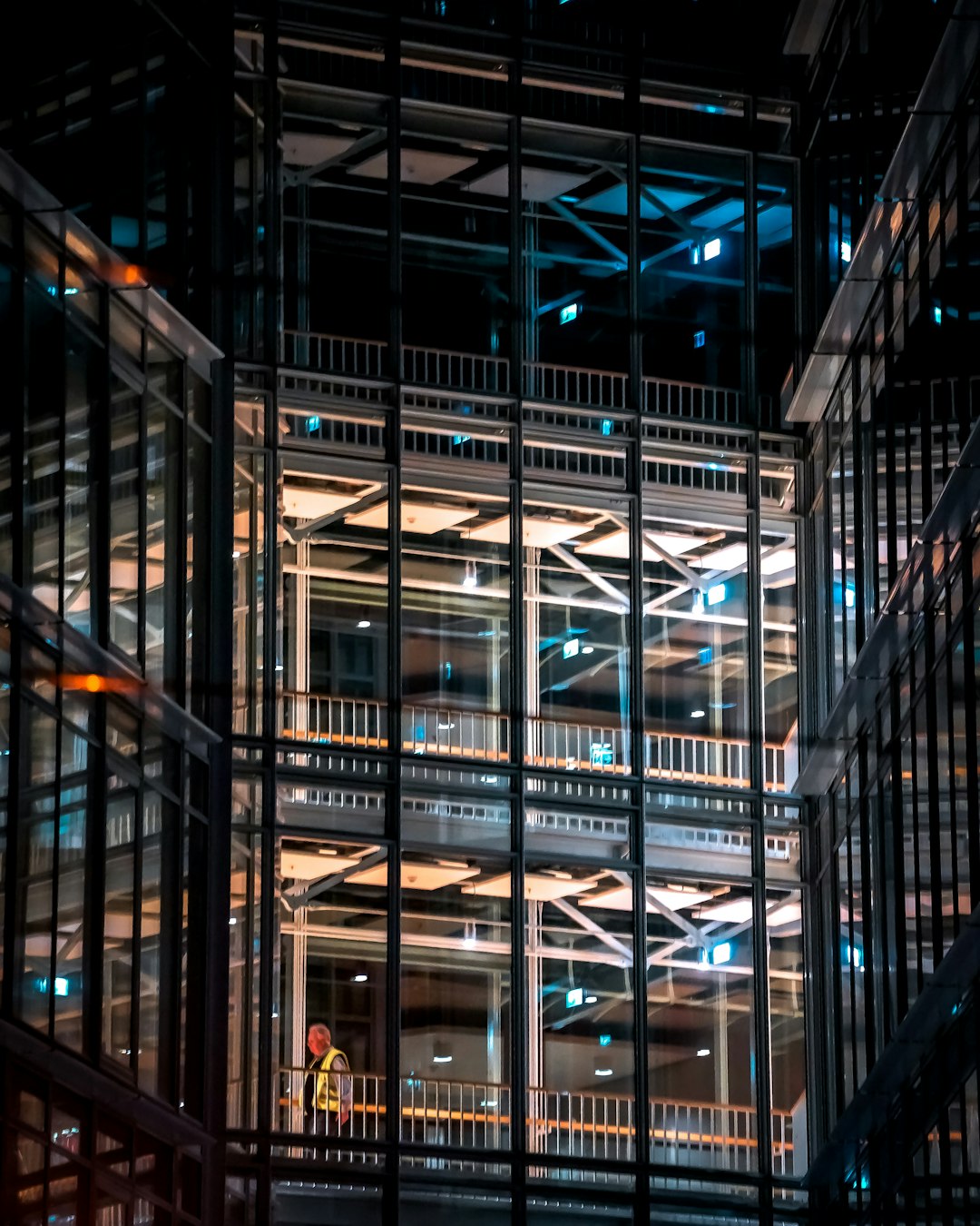 people walking on sidewalk near glass building during night time