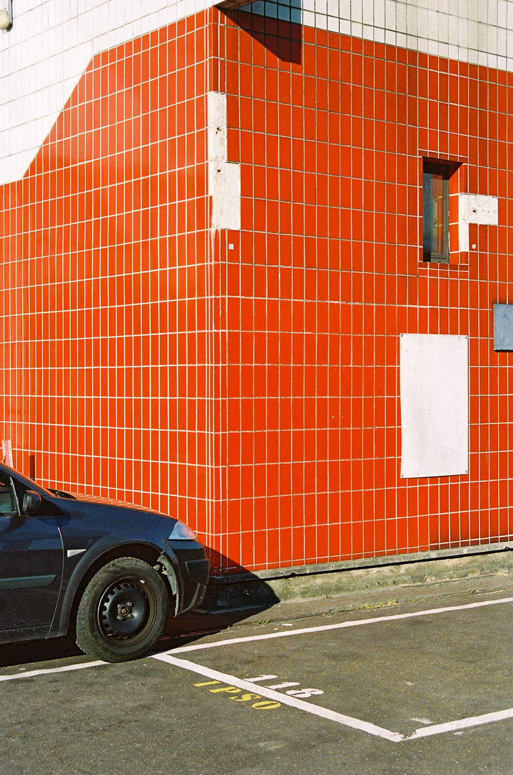 black car parked beside brown brick wall