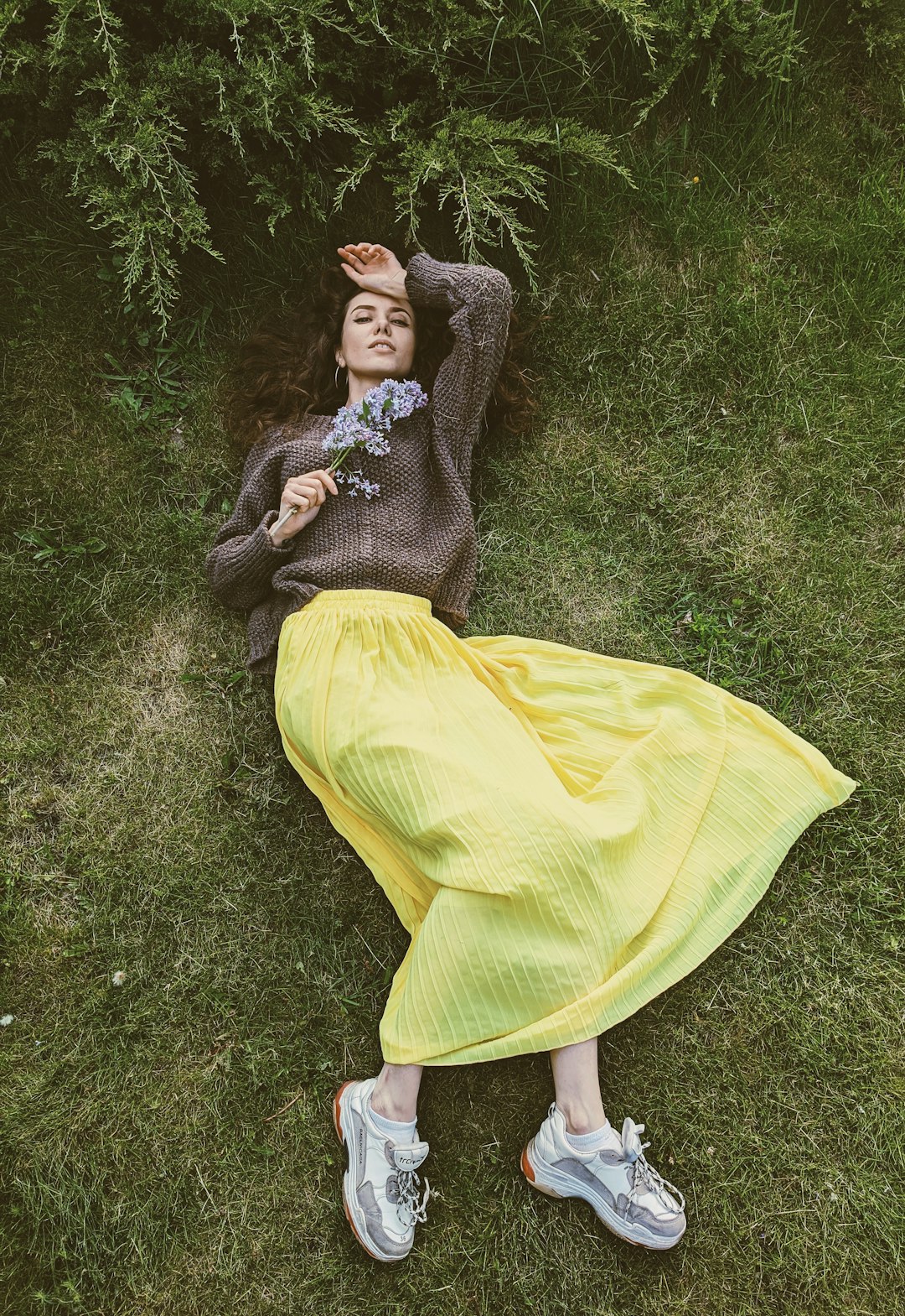 woman in black long sleeve shirt and yellow skirt sitting on green grass