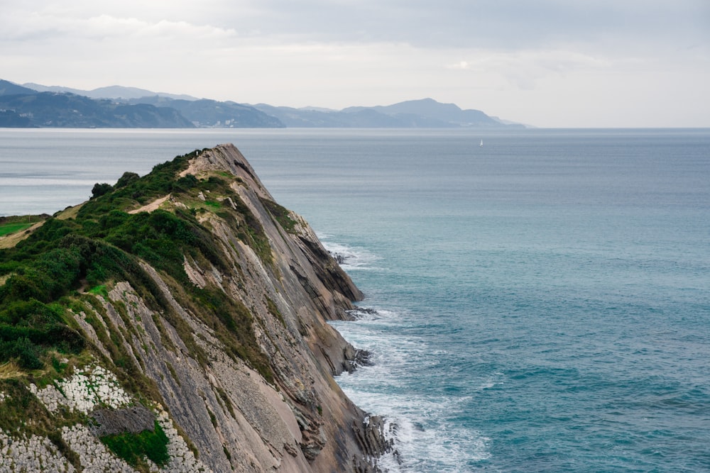 green and brown rock formation beside sea during daytime