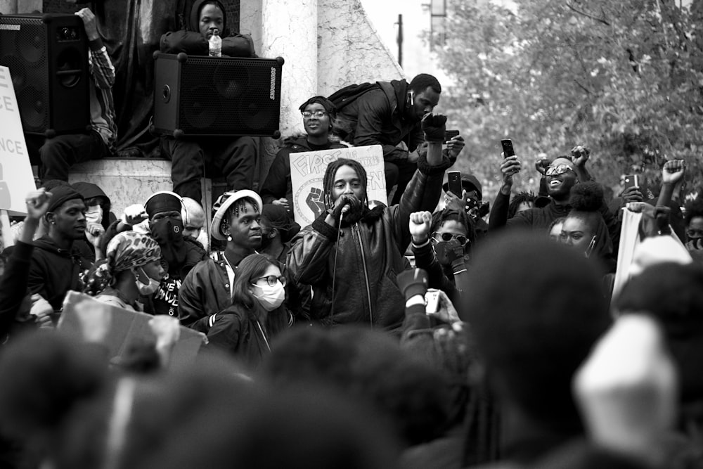 grayscale photo of people standing and holding a black laptop computer