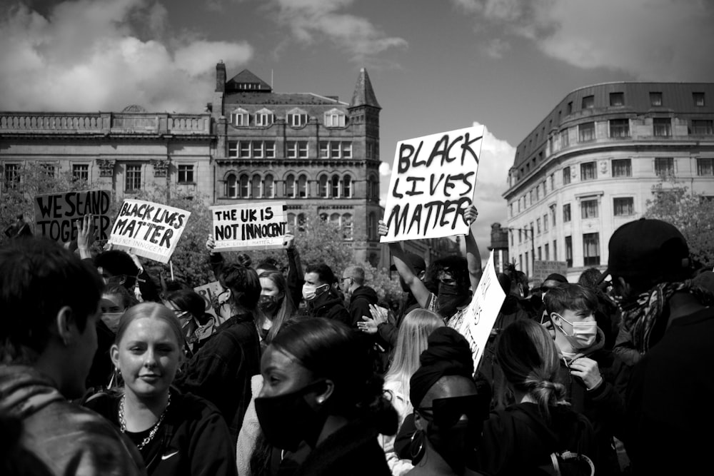 Graustufenfoto von Menschen, die sich in der Nähe des Gebäudes versammeln