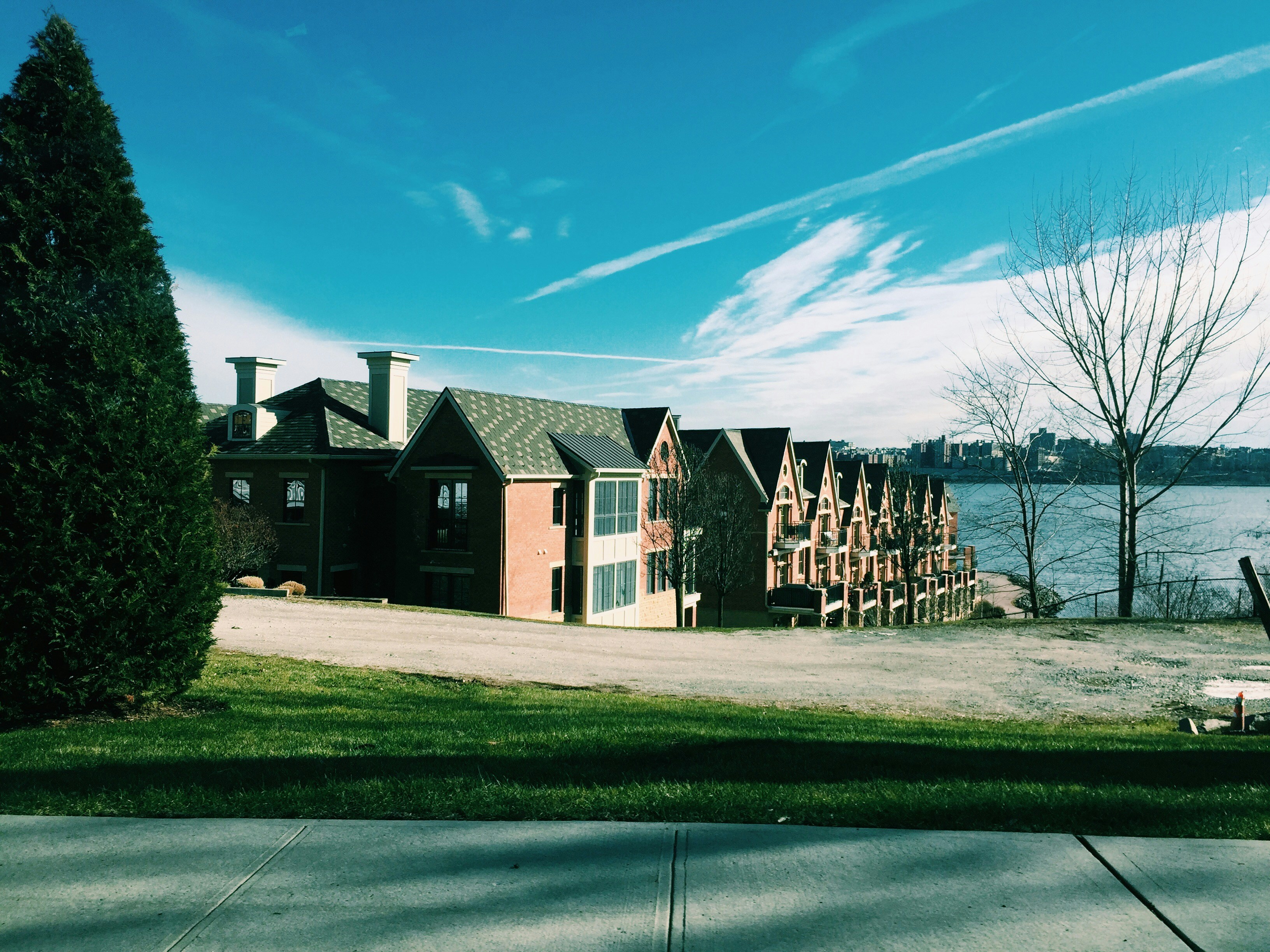 Brown and white wooden house near green grass field under blue sky ...