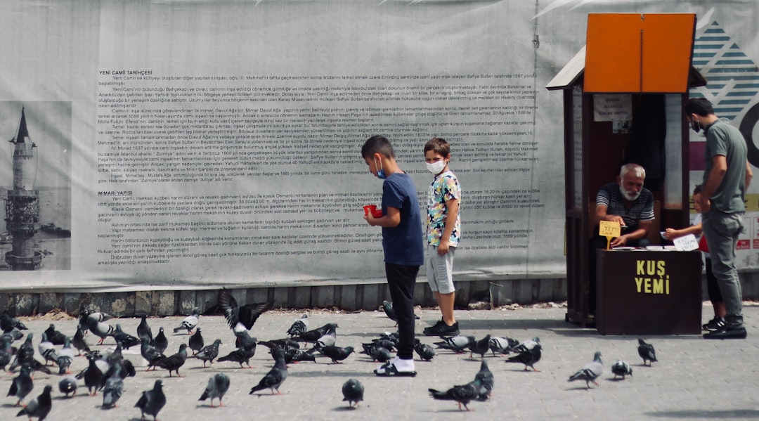 man in blue and white crew neck t-shirt and gray pants standing on gray concrete