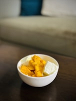 Bright mango pulp poured into a small glass bowl with fresh mango slices beside it.