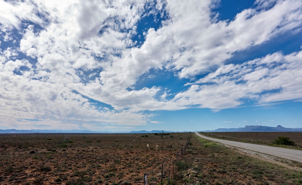 gray asphalt road under blue sky and white clouds during daytime