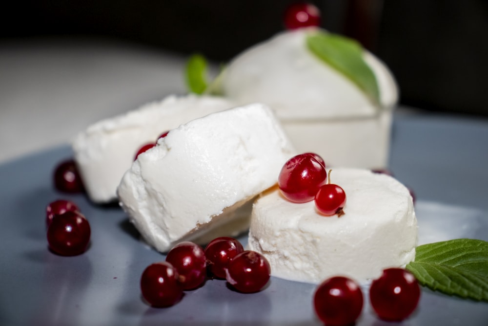 weißer und roter Kuchen mit roten runden Früchten auf weißem Keramikteller