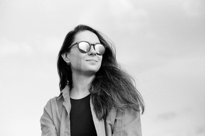 Woman in a black shirt and brown coat wearing sunglasses