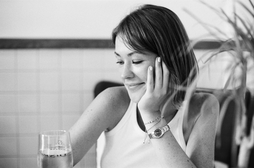 woman in white tank top holding her face