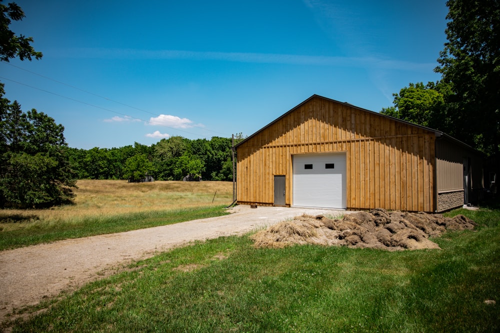 brown wooden house on green grass field under blue sky during daytime