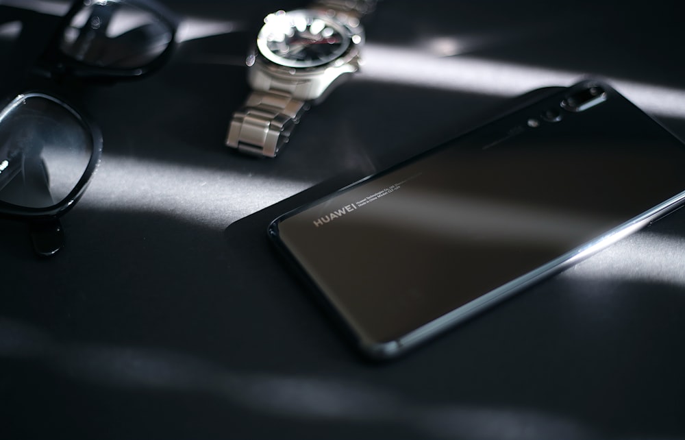 Smartphone Android Samsung noir à côté de la montre analogique ronde argentée