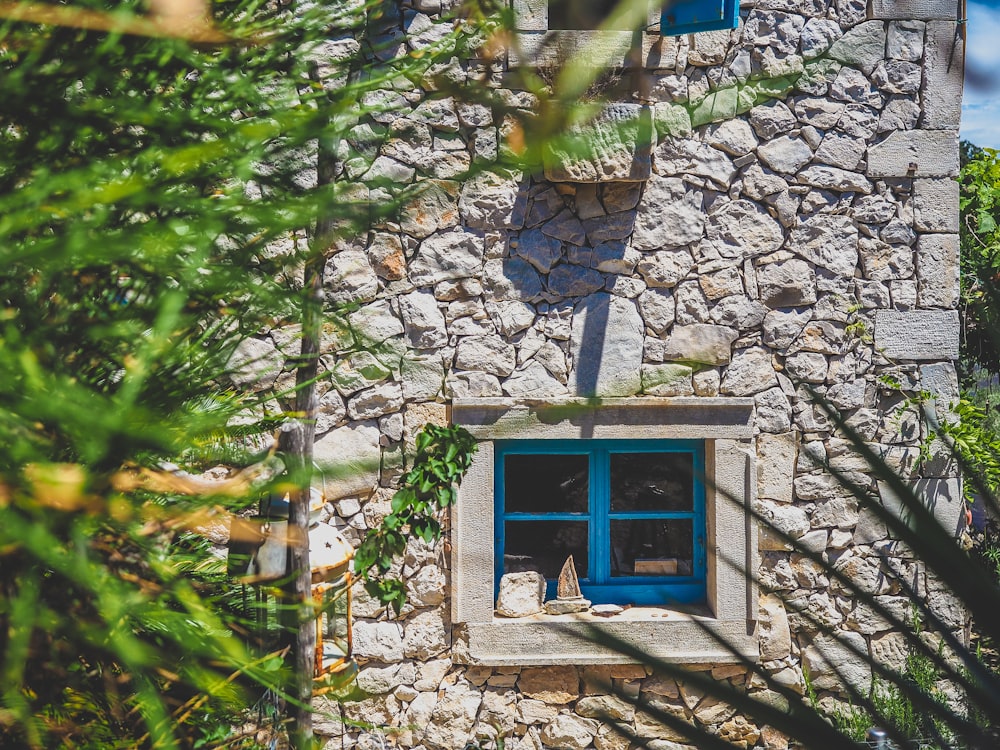 blue wooden framed glass window on gray brick wall