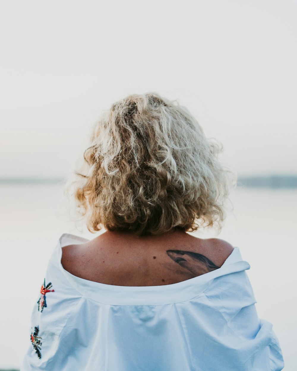 woman in white shirt looking at the sea during daytime