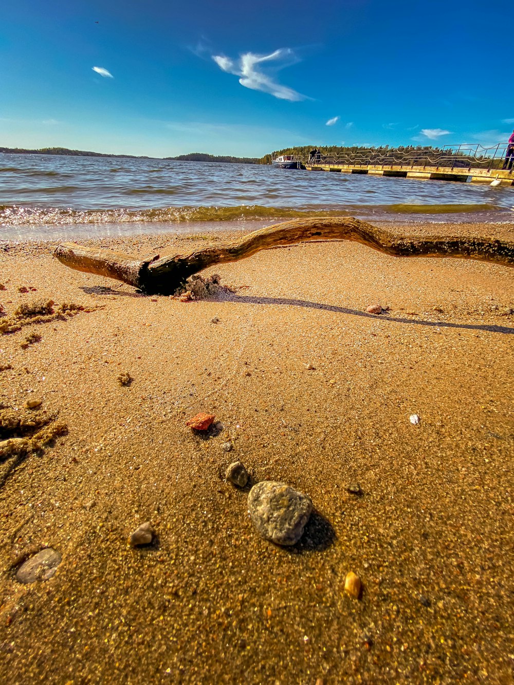 roches brunes et grises sur sable brun près du plan d’eau pendant la journée