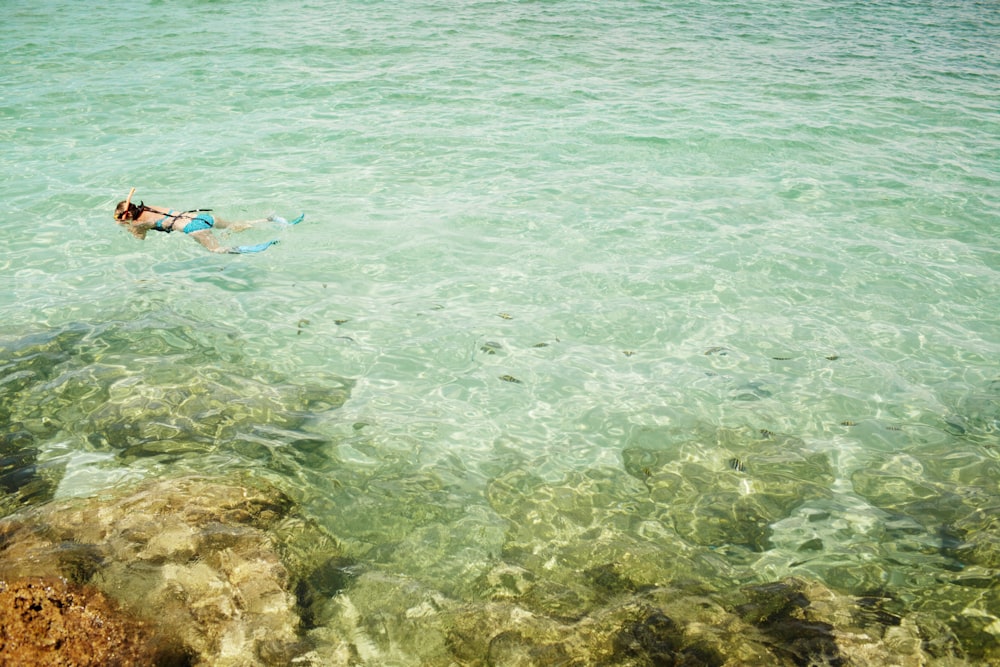 person in blue shorts swimming on sea during daytime