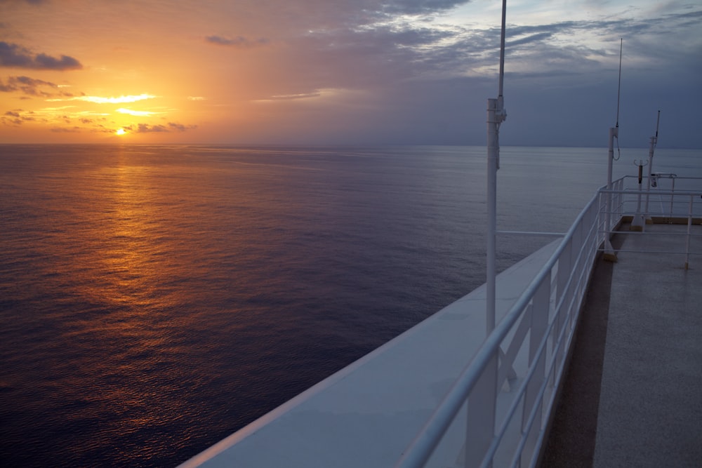 white metal railings near body of water during sunset