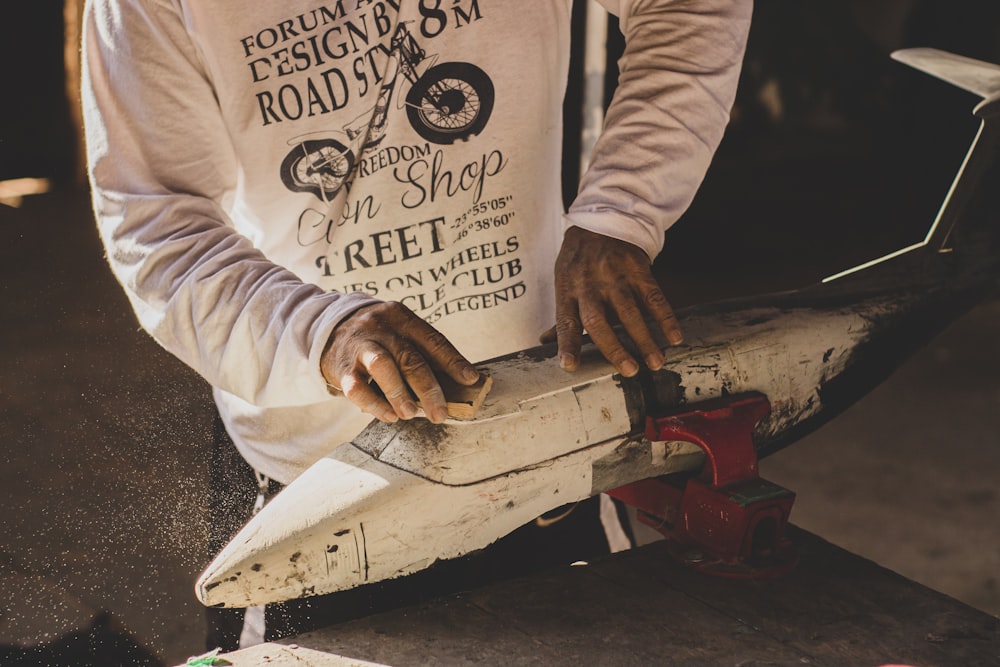 person in white long sleeve shirt holding brown wooden knife