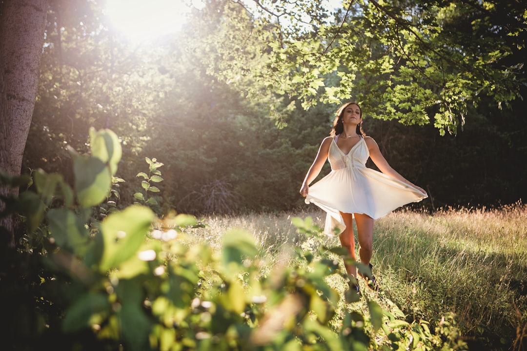 woman in white dress standing on green grass field during daytime