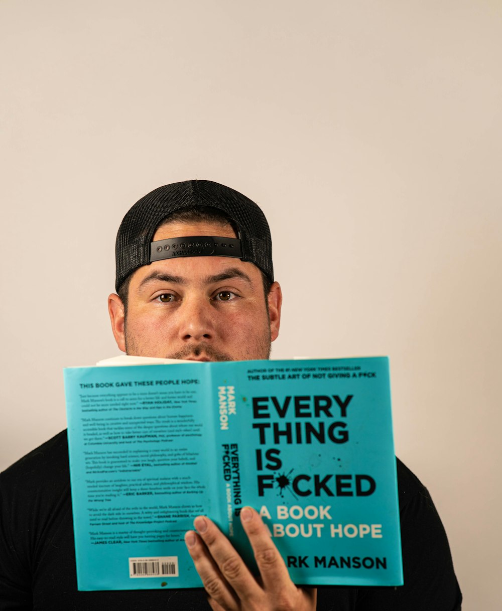 man in black shirt holding blue book