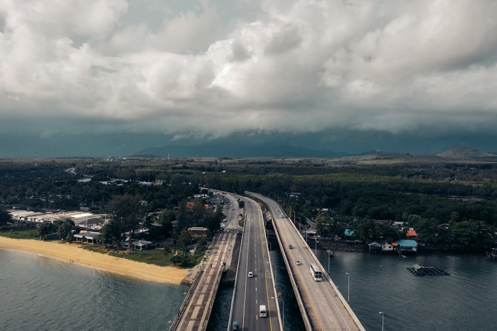 gray concrete road near body of water under white clouds during daytime