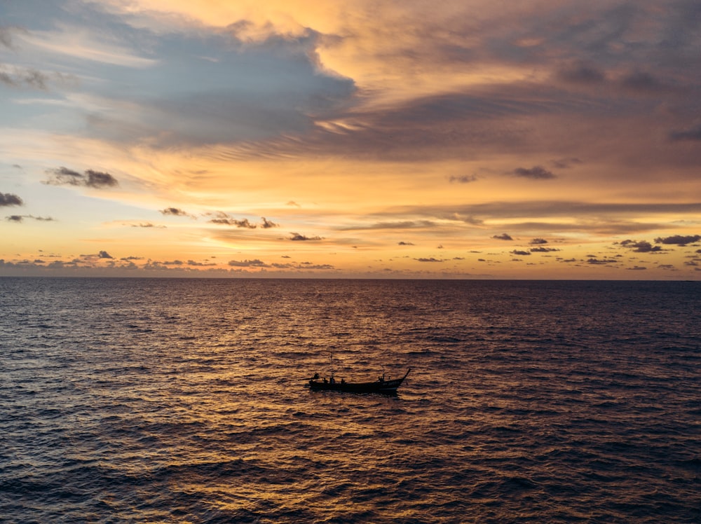 silhouette of boat on sea during sunset