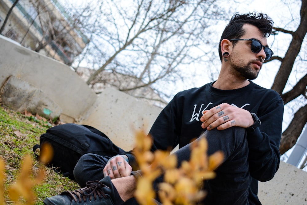 man in black crew neck shirt sitting on green grass field during daytime