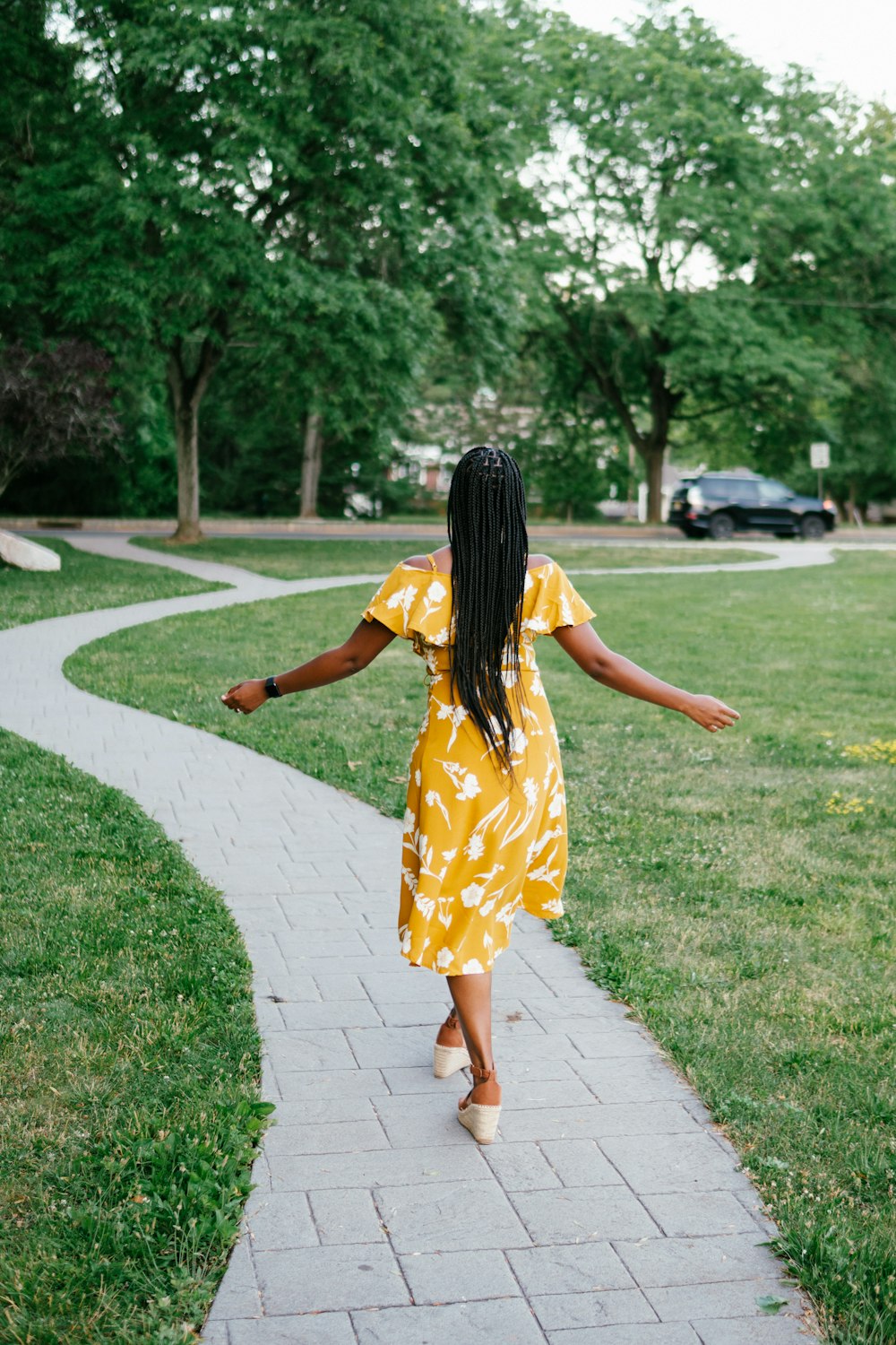 woman in yellow and white floral dress walking on pathway during daytime