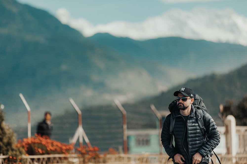 man in black jacket and black backpack standing on field during daytime