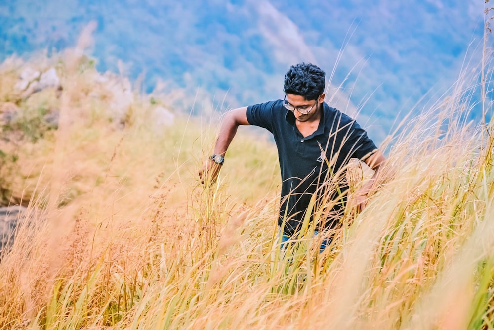 man in black crew neck t-shirt standing on brown grass field during daytime