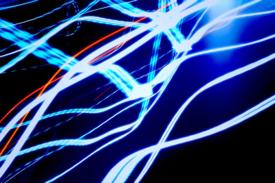 A dynamic display of vibrant blue and orange light trails against a dark background, creating an abstract and energetic visual effect.