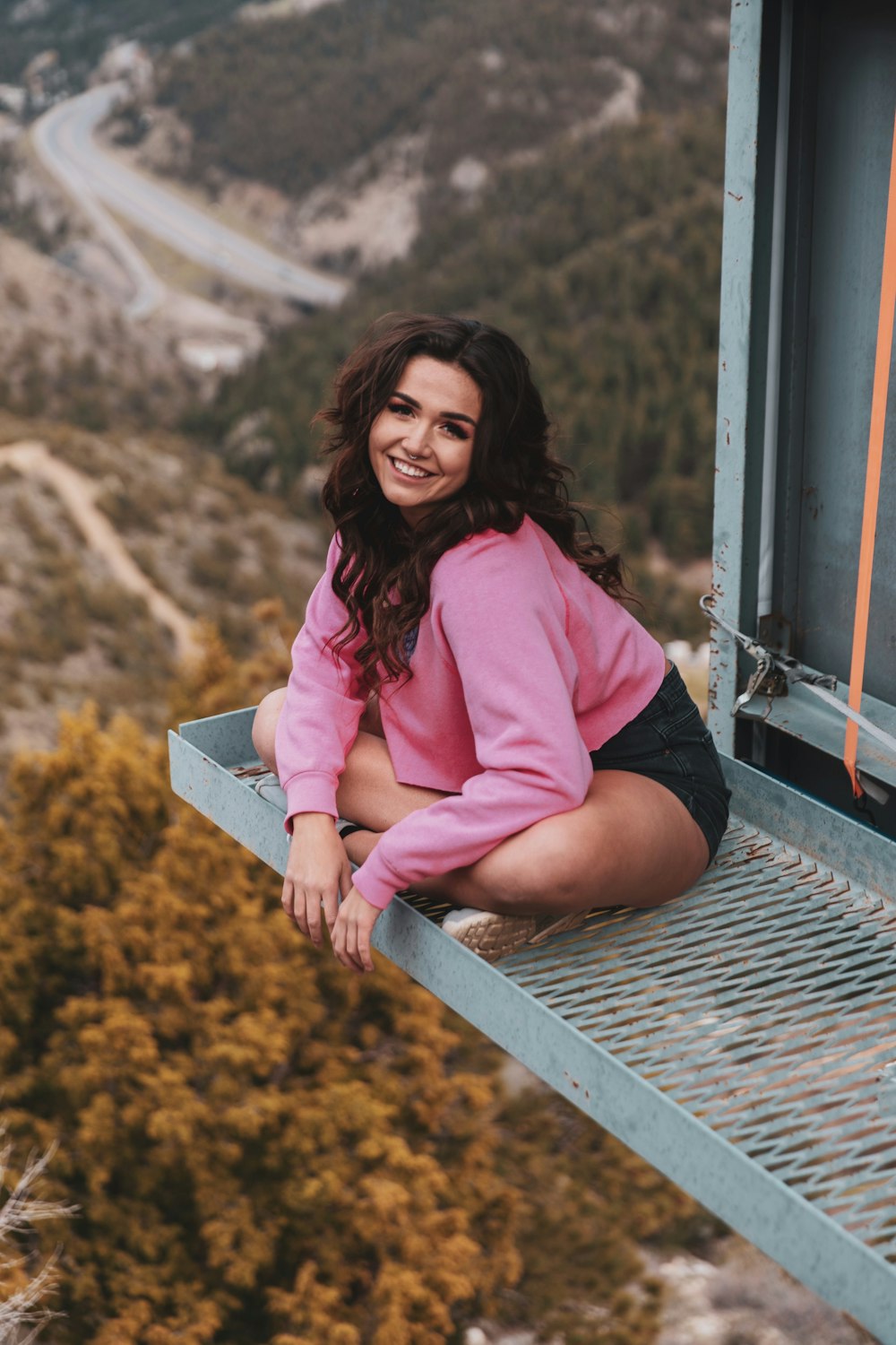 woman in pink long sleeve shirt sitting on train rail during daytime