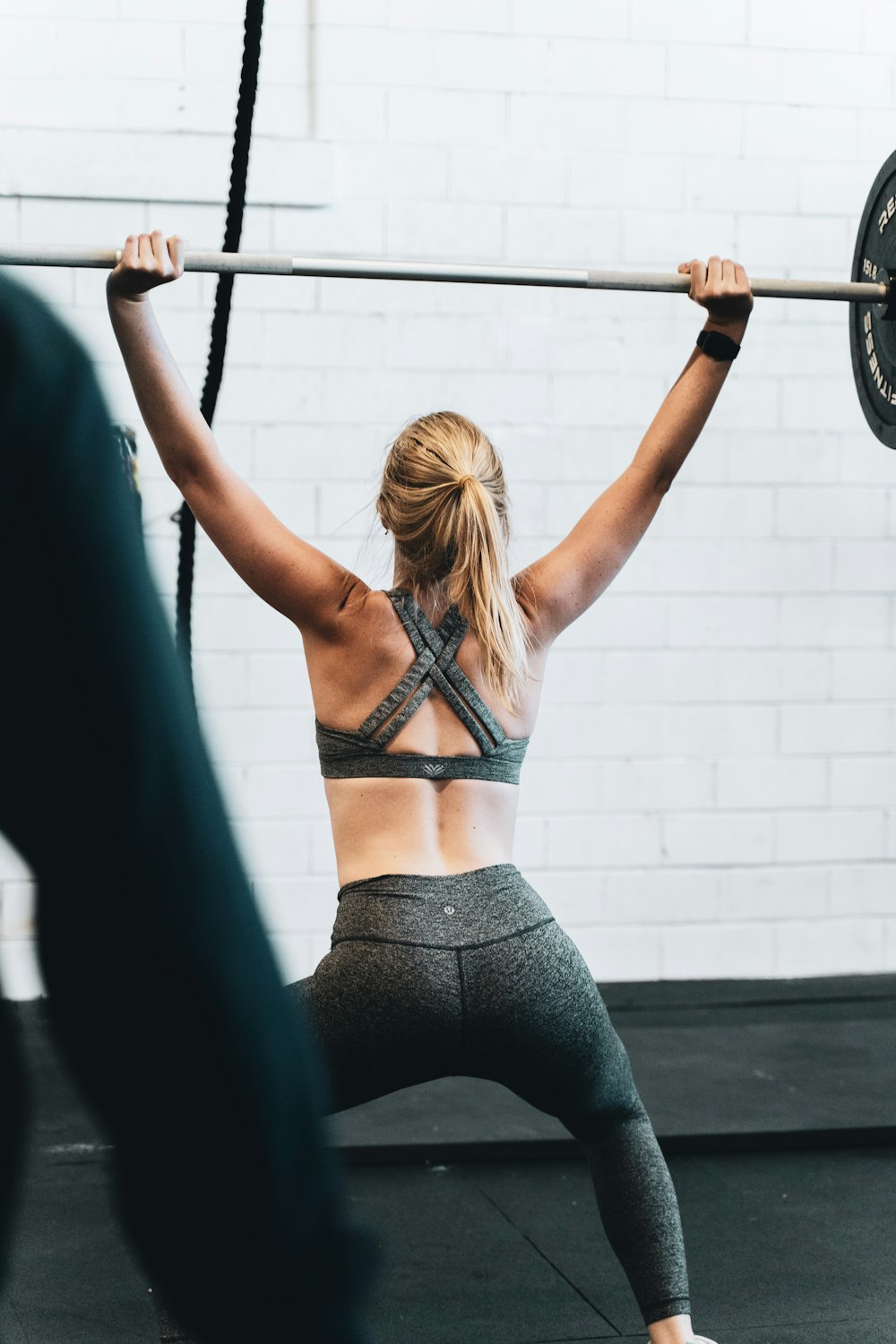 woman in black brassiere and black leggings holding on gray metal bar