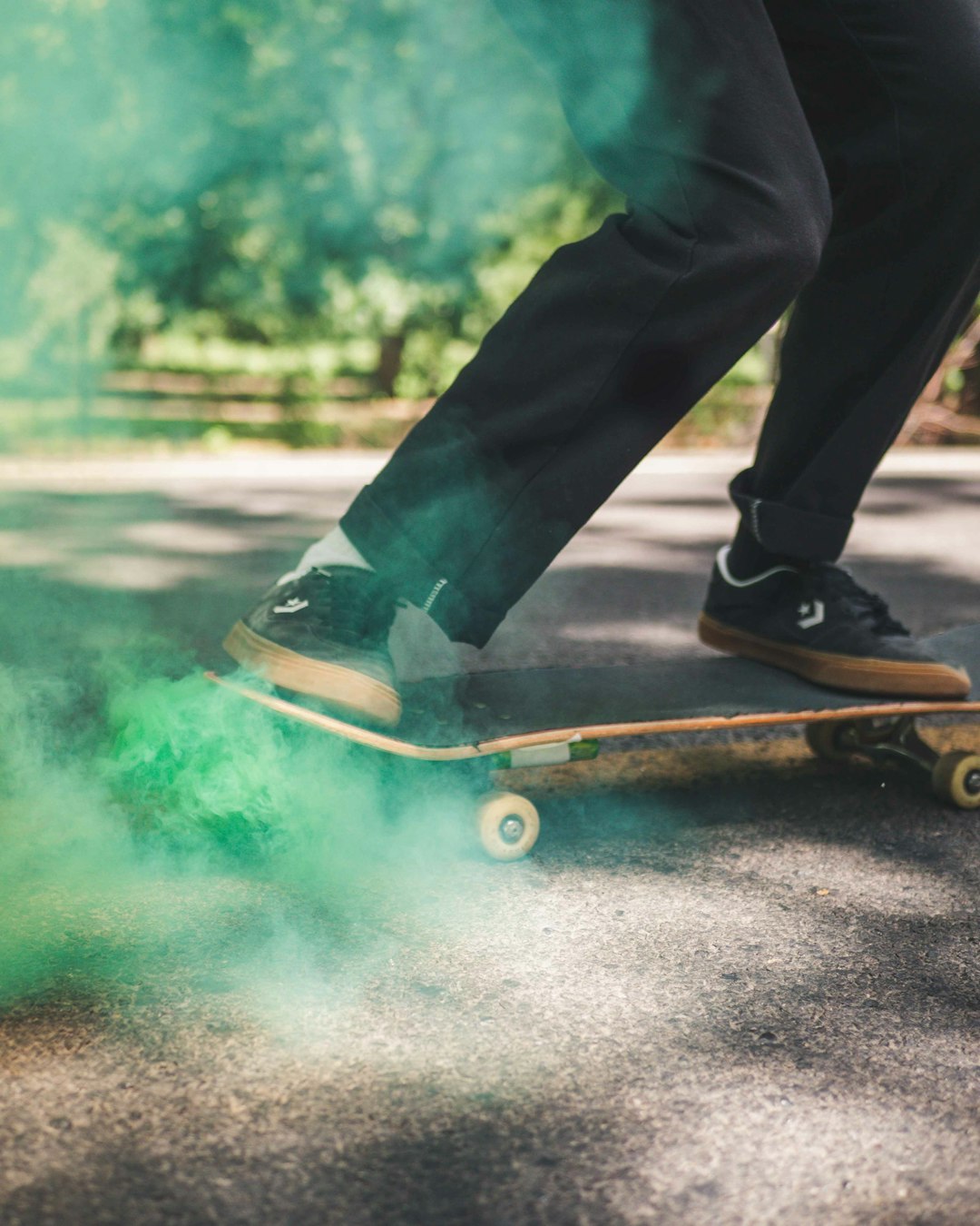 person in black pants and black shoes sitting on brown wooden skateboard