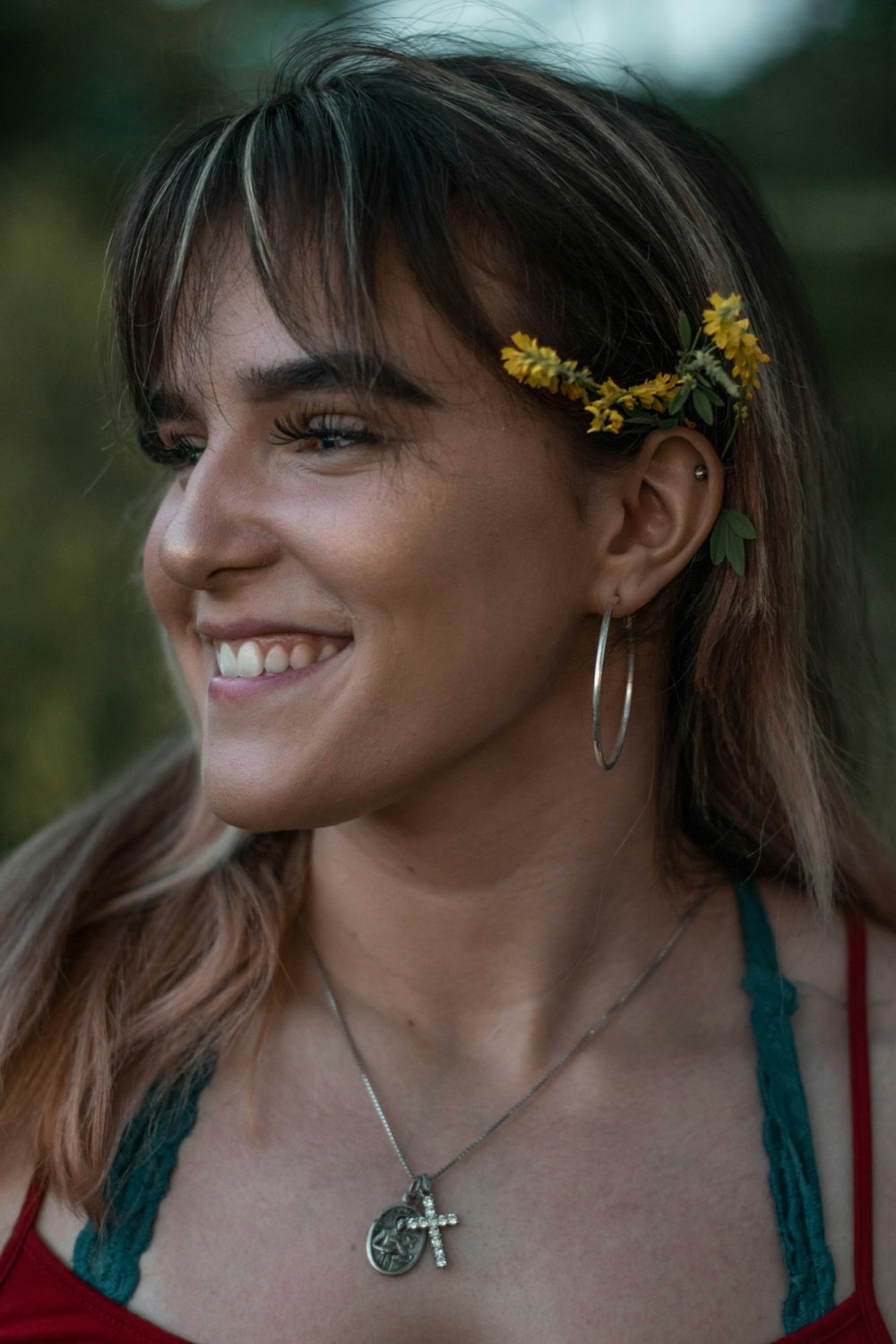 woman in blue tank top with yellow flower on ear smiling