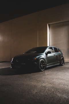 A sleek black sedan parked under soft lighting against a dark backdrop.