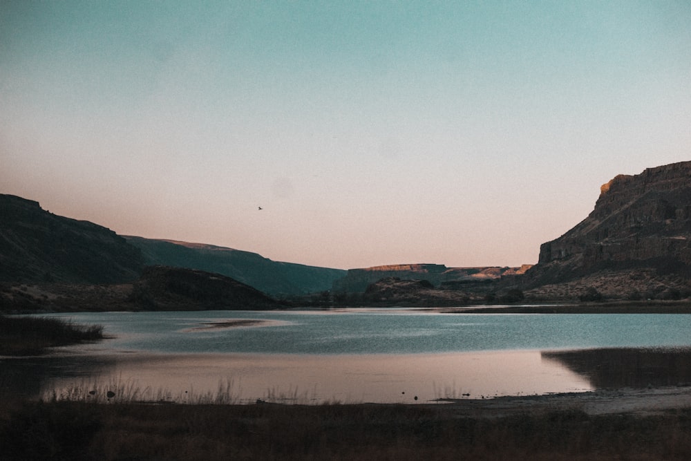 body of water near mountain during daytime